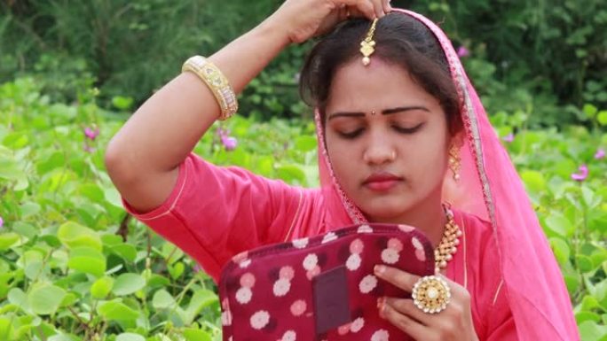 一位印度美女穿着Rakhdi坐在花园里微笑着 (Marwari新娘称其为maang tikka)
