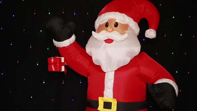 大充气圣诞老人娃娃在圣诞帽红色西装外套黑色手套和礼物，礼品盒在空中旋转。
