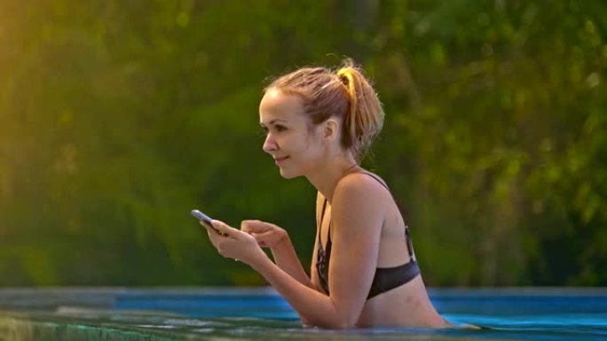 女孩看着智能手机，并在水潭侧视图中休息