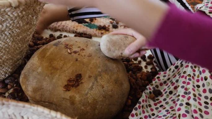 一名摩洛哥妇女打开摩洛哥坚果，提取果仁，用于传统手工摩洛哥坚果油的生产。