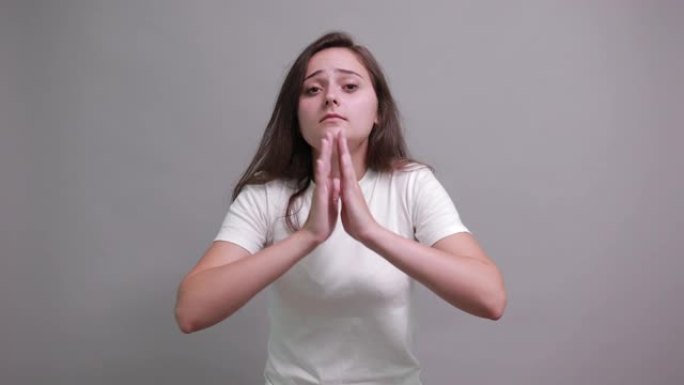 失望的女人双手合十，祈祷，看着相机