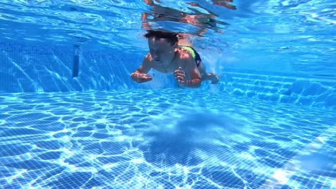 男孩在游泳池的水下游泳。