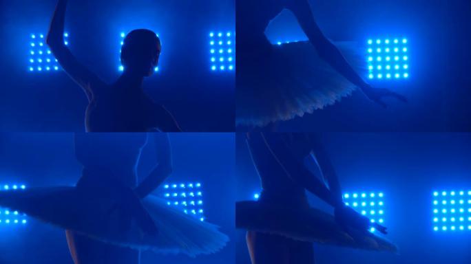 漂亮的芭蕾舞演员优雅地跳舞。演出前的芭蕾彩排。美丽苗条身材的轮廓。带烟雾和蓝色霓虹灯的黑暗工作室。特
