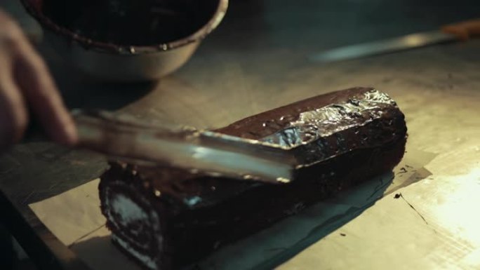 用抹刀将巧克力撒在可可奶油瑞士卷上。