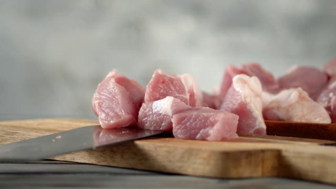 一块块生猪肉烤肉串落在切菜板上。