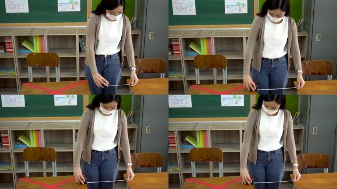 在小学，亚洲女教师戴着口罩测量课桌之间的距离。