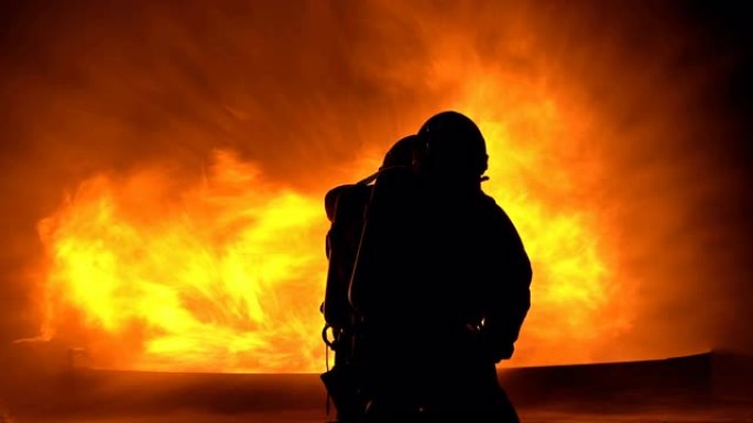 男性消防员使用消防水带扑灭大火