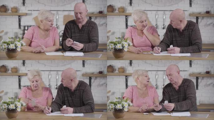 白人老年夫妇处理账单的肖像。秃头男人和金发女人坐在桌子旁聊天。高级配偶解决他们的收入和支出。财务，退