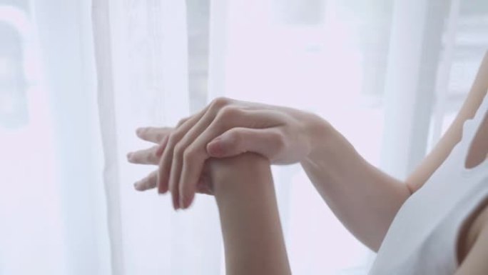 亚洲女性在家庭工作室用乳液在手。白霜擦洗治疗皮肤状况。