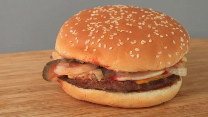 桌子上躺着一个漂亮多汁的大汉堡。快餐。卡路里含量高的食物