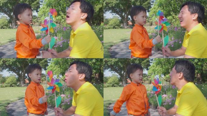 亚洲父亲和他的孩子在风车玩具上玩得很开心，爸爸和儿子在夏天在大自然上玩风车
