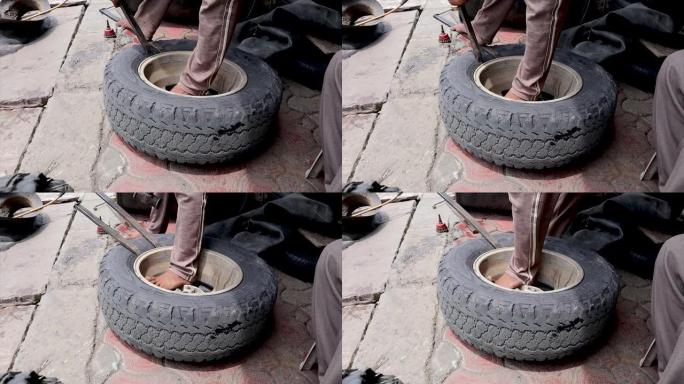 一名印度男子正在修理一辆大型卡车轮胎。从其磁盘/车轮上卸下橡胶轮胎。