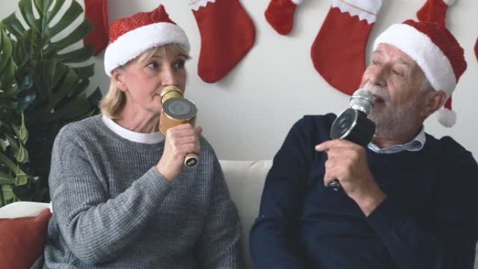 年长的高加索老人老人和女人很高兴在装饰有圣诞树的房间里一起唱歌