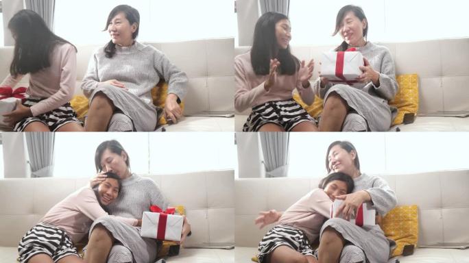 亚洲女孩坐在家里的沙发上给妈妈送礼盒惊喜。