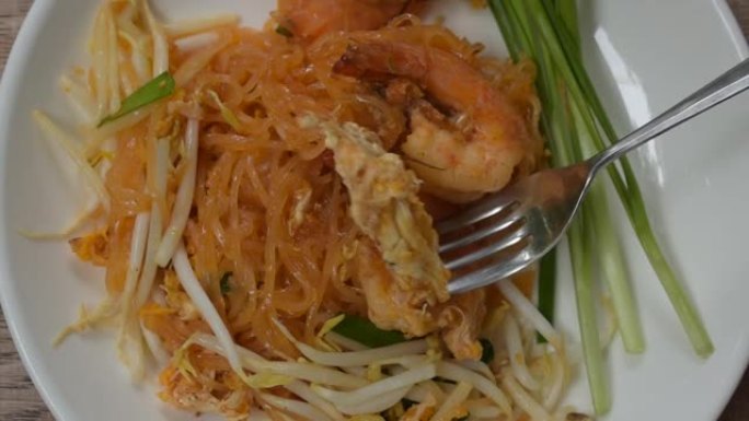 用叉子捅虾和鸡蛋的泰式炒米粉