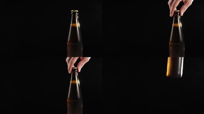 新鲜啤酒。手从黑色背景下的木制桌子上拿出一个棕色的瓶子，里面装着美味的精酿啤酒。水滴冷新鲜啤酒。准备