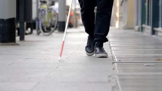 一个盲人走在城市的人行道上。自主权,障碍