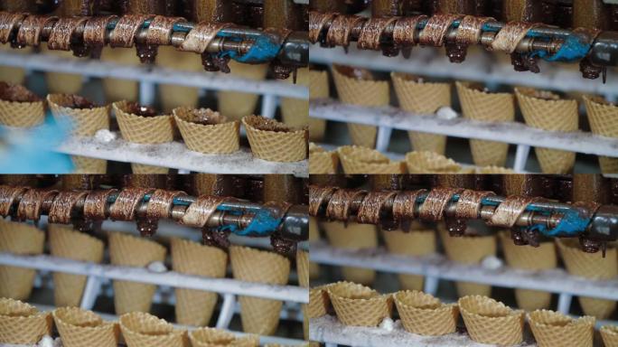 机器人机器会自动将巧克力倒入威化饼杯中。用于生产冰淇淋蛋筒的输送机自动线。威化杯和圆锥体。大型工业生
