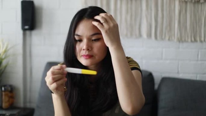 悲伤的亚洲妇女怀孕使用怀孕测试