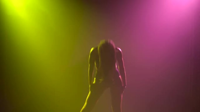 年轻性感的女人在美丽的演播室灯光的背景下热情地跳舞。细长身体的轮廓特写