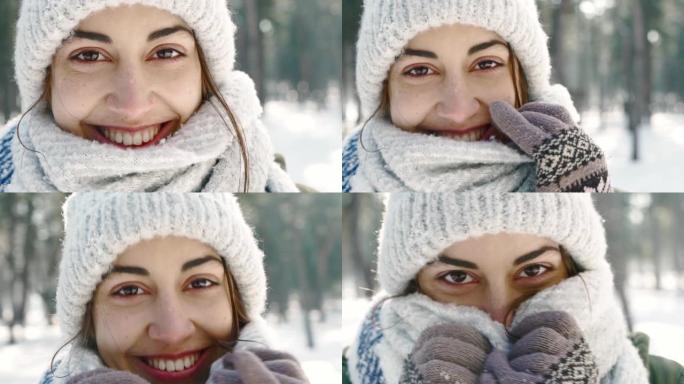 在寒冷的晴天，白雪皑皑的冬季公园里，穿着羊毛帽和长长的温暖围巾的美丽微笑女人的极端特写肖像。女人看起
