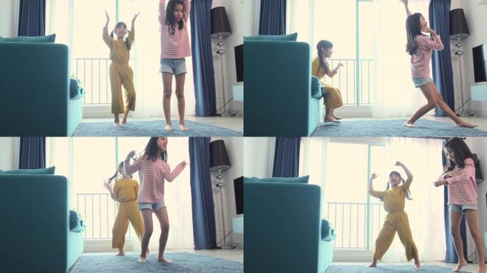 亚洲女性儿童兄弟姐妹在客厅一起玩乐。姐妹在沙发上一起跳舞。家庭在家里。人的概念