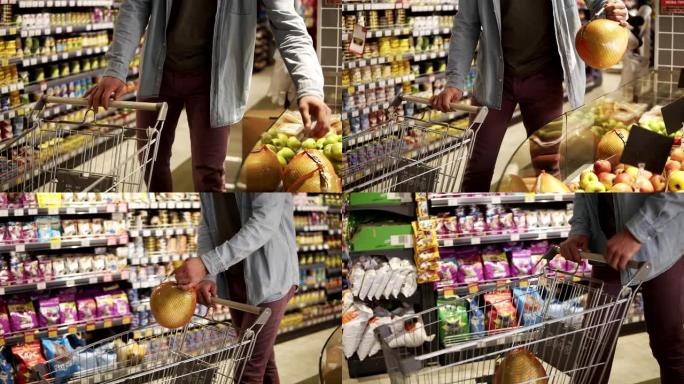 在一家杂货店超市的农产品部门，穿着蓝色衬衫的无法辨认的男人在购买水果和蔬菜的镜头。带着柚子，把它放进
