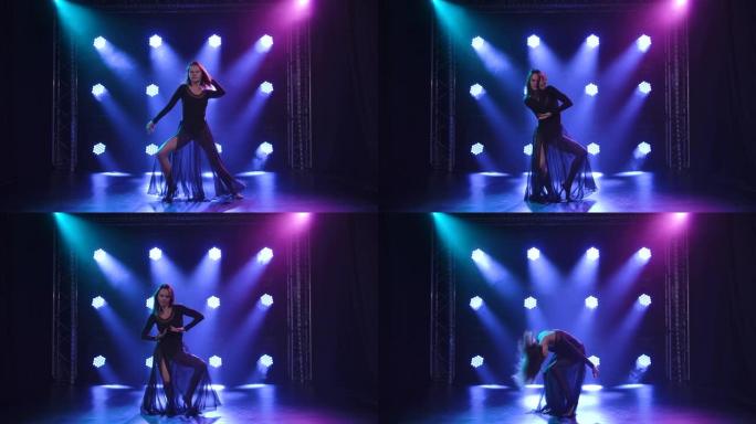 冲动的表演者在蓝色灯光的黑色背景上以当代风格的contempp编舞跳舞。慢动作