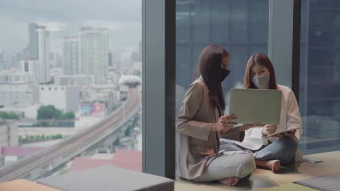 混合种族夫妇商务女性在办公室工作时使用笔记本电脑戴口罩