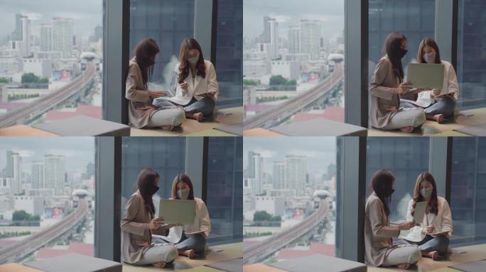 混合种族夫妇商务女性在办公室工作时使用笔记本电脑戴口罩