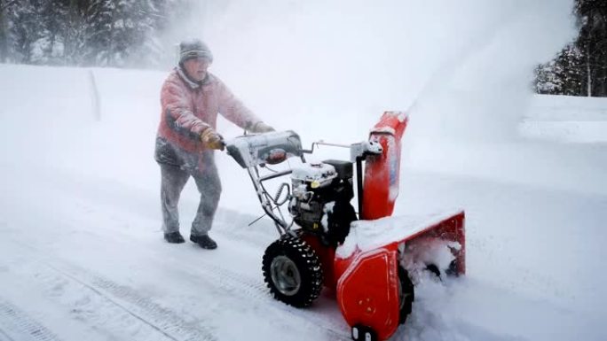 高级男子在乡村车道上吹雪