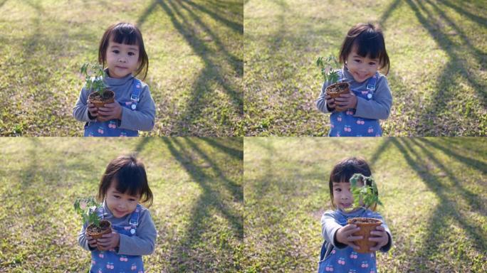 亚洲小女孩在大自然背景下的小盆中种植树木。