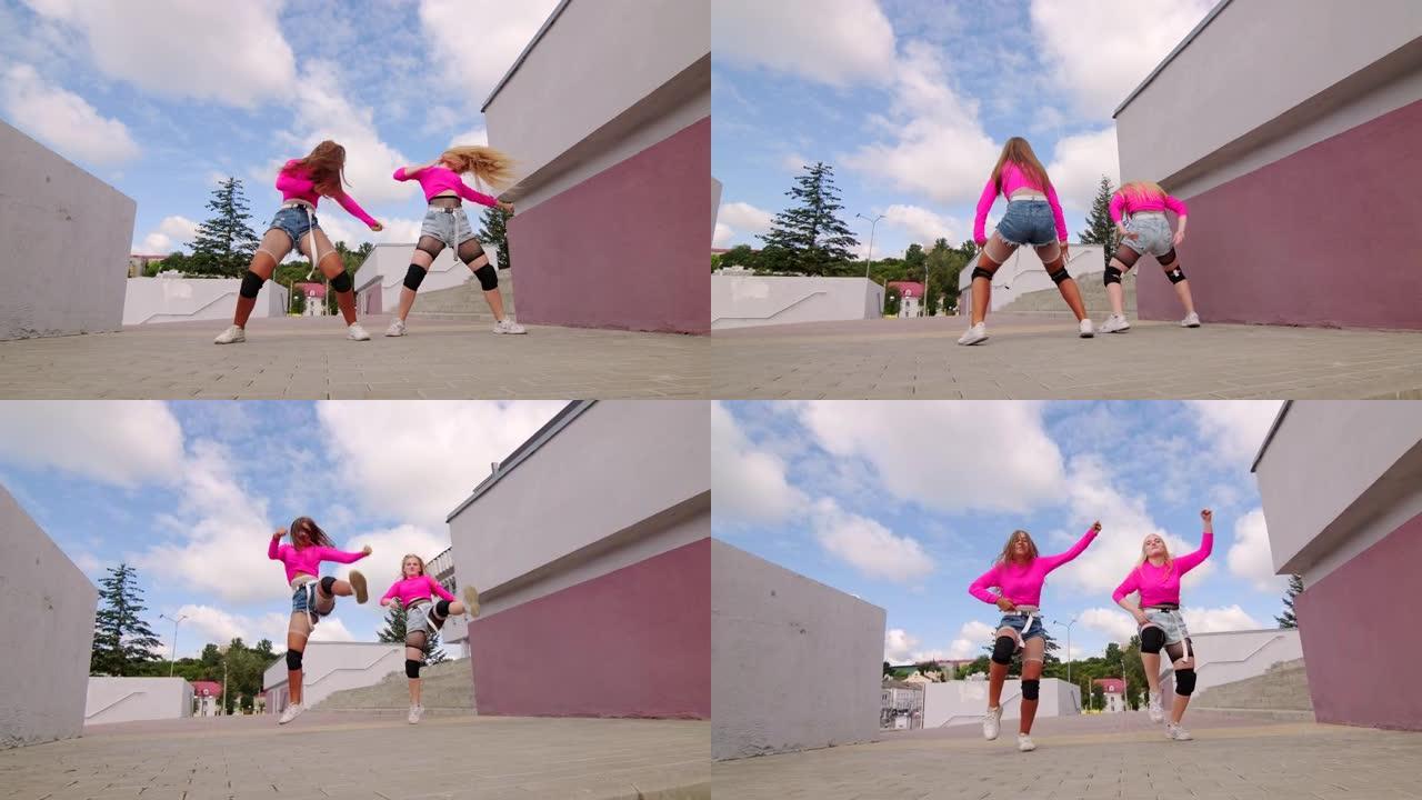 两个漂亮的年轻女孩穿着短裤跳舞自由风格的街舞，在城市户外进行嘻哈舞蹈。慢动作