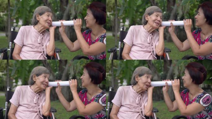 女儿用纸管与听力受损的老年妇女交谈