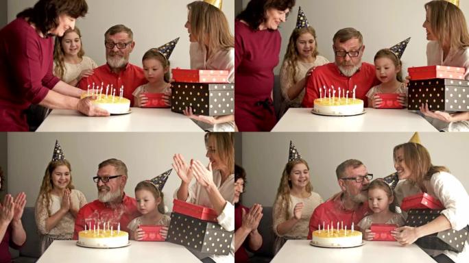 大型友好的多代家庭站在一起，看着祖父在生日蛋糕上吹蜡烛
