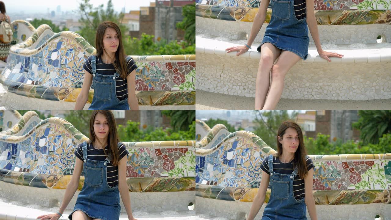 公园奎尔的主露台。一个快乐的年轻女子坐在瓷砖蛇形长椅上。巴塞罗那。西班牙。4K