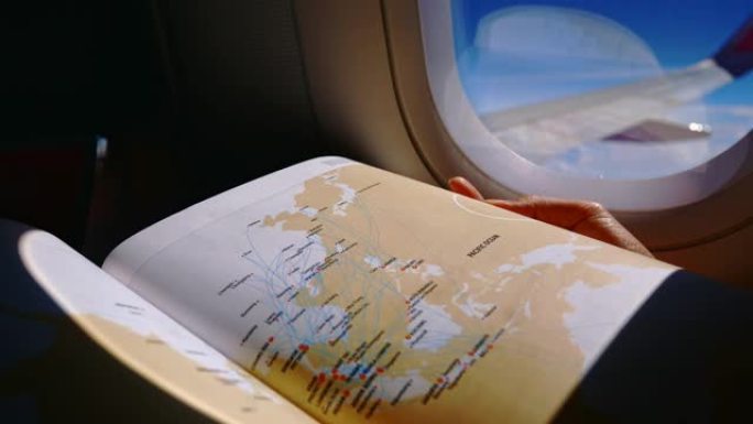 女性旅客坐在机舱阅读书中的飞机休息座位上。