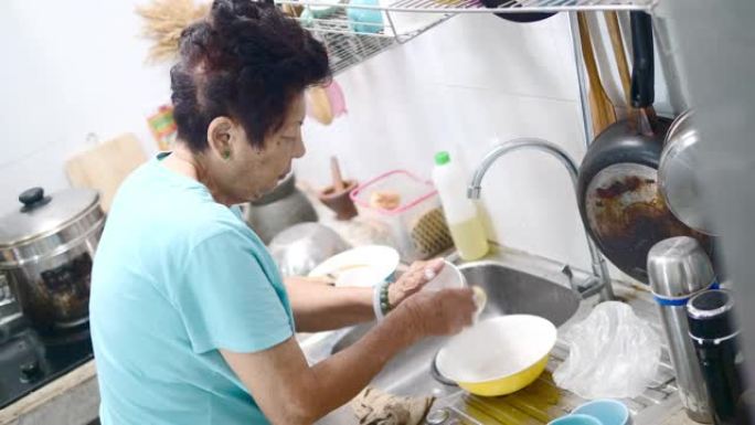 亚洲老年人在家做饭时在厨房洗碗，生活方式理念。