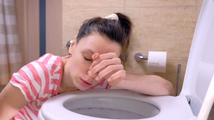 年轻的病人正在上厕所，呕吐坐在家里的地板上，出现流感症状。