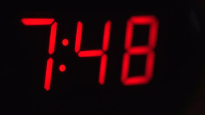 黑色数字时钟屏幕的特写显示7.40。黑色背景上闪烁红色数字。现代定时器系统和霓虹灯、电动报警装置