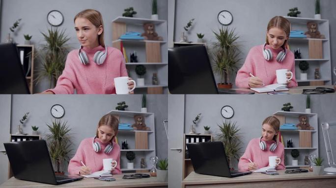 穿着粉红色毛衣的漂亮昂扬的年轻金发女子，看着电脑，把必要的笔记写进日记