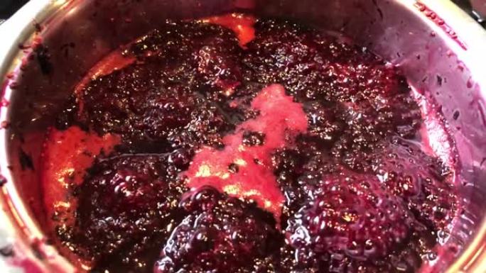 在平底锅里煮黑莓做果酱。