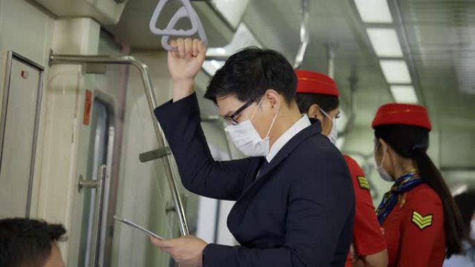 亚洲商人乘坐轻轨上班时戴着面具。预防公共场所的冠状病毒、细菌与人接触。商务人士在高峰时间开会时使用平