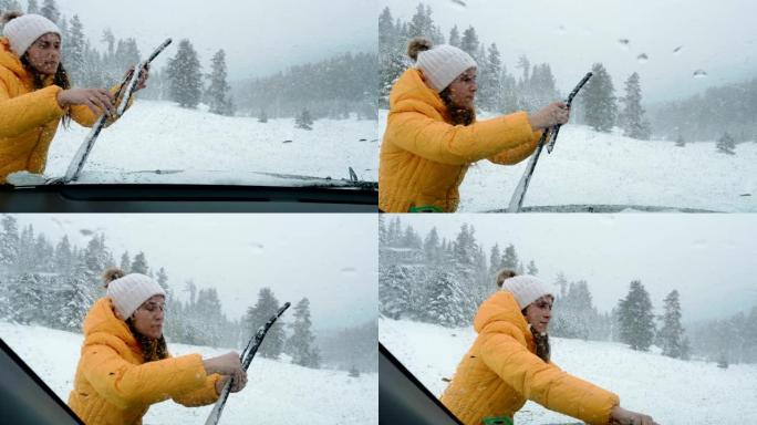 驾驶员的POV在中午在积雪覆盖的道路上行驶，第一场雪落下。暴风雪和降雪。年轻女子从冰上清洁挡风玻璃刮