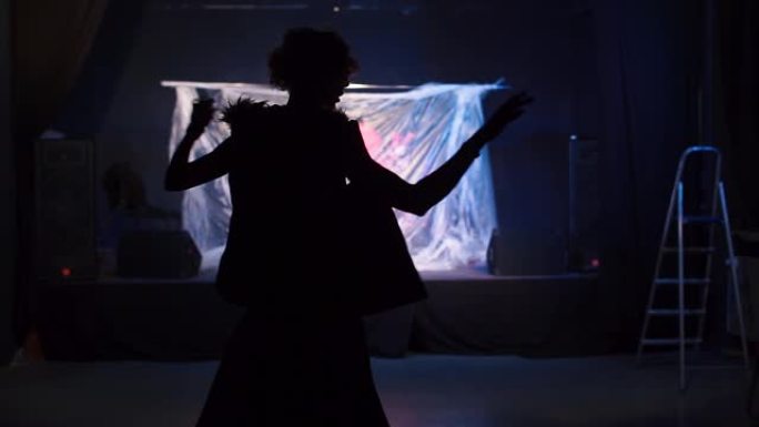 一个女孩在黑暗中跳舞动作的剪影。