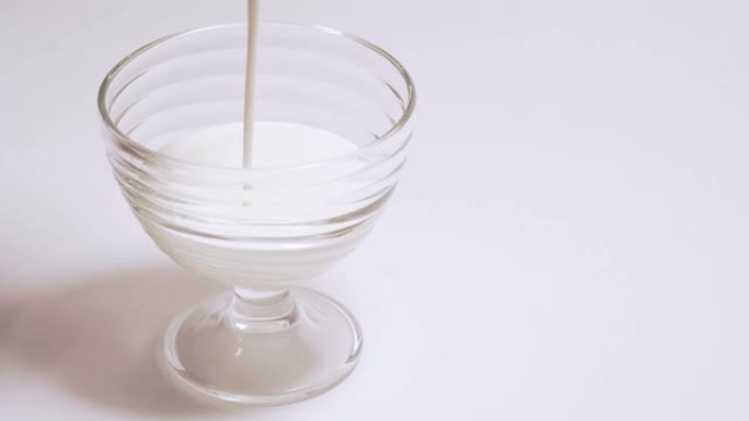玻璃杯中的有机奶昔。一个人将开菲尔倒入隔离4k的透明容器中