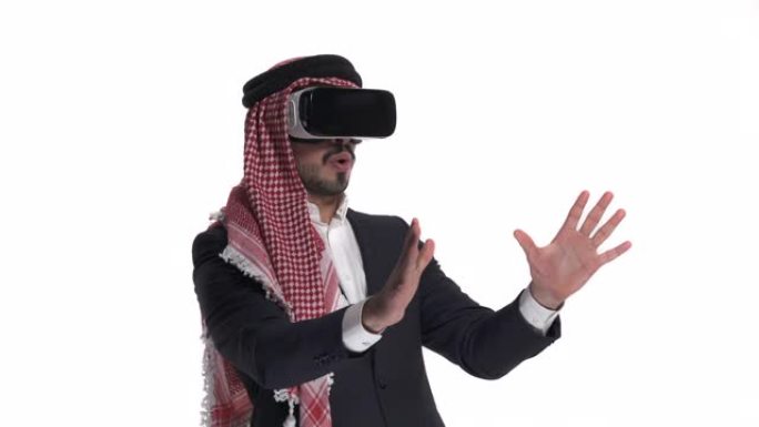 惊讶的阿拉伯大胡子男子使用VR耳机玩游戏，孤立在白色。3D网络技术概念。