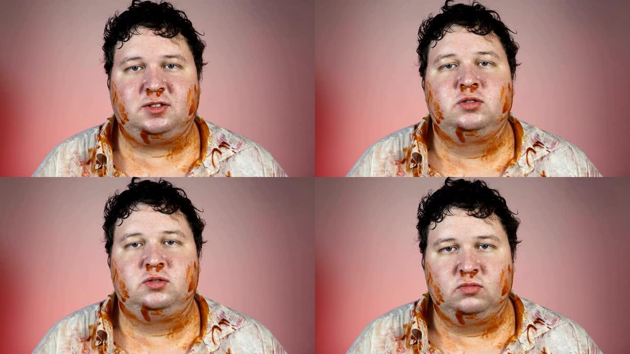 饭后的男人。胖胖的肮脏男人，番茄酱在红色背景下散布在脸上。不健康的概念