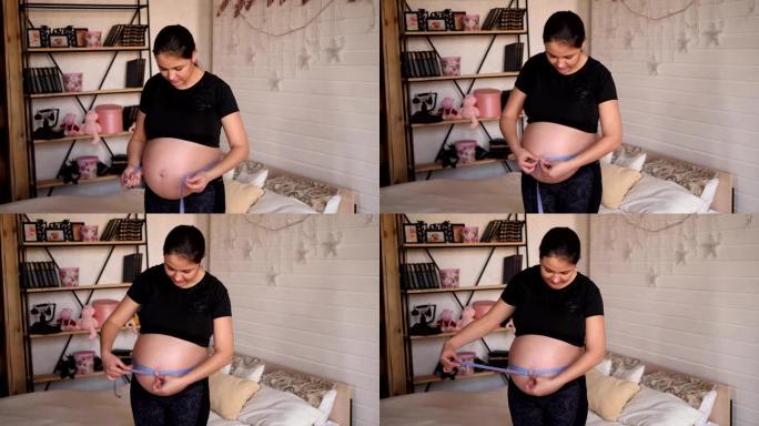 孕妇拿着厘米胶带测量腹部的肖像。