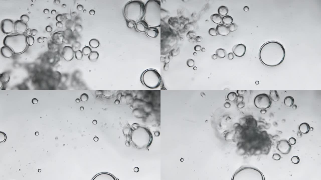 水中的气泡同时将水倒入玻璃中，照片来自水下角落。创意抽象背景，银色调风格。